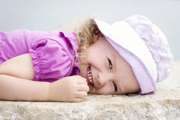 Happy little girl lying on the rock