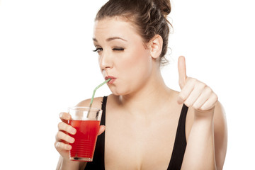 young woman drinking a cocktail and showing thumbs up