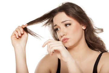 dissapointed young woman looks at the tops of her hair