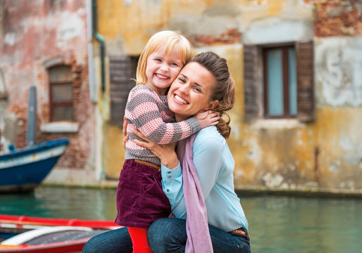 Portrait of happy mother and baby girl hugging while in venice