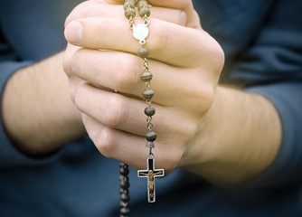 man prays with a rosary in hands