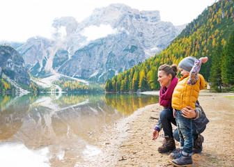 Mother and baby throwing stones on lake braies in south tyrol