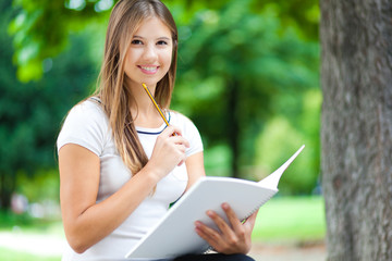 Obraz premium Female student reading a book at the park