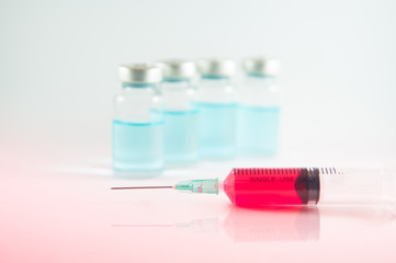 Red liquid in injection syringe and vials background