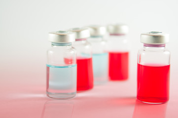 Red and blue liquid in injection vials on red floor effect