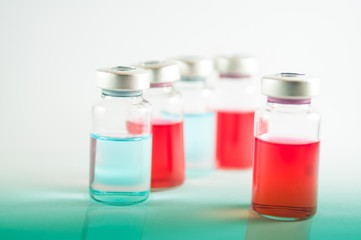 Red and blue liquid in injection vials on red floor effect