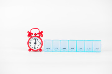 weekly pill box and red clock show medicine time