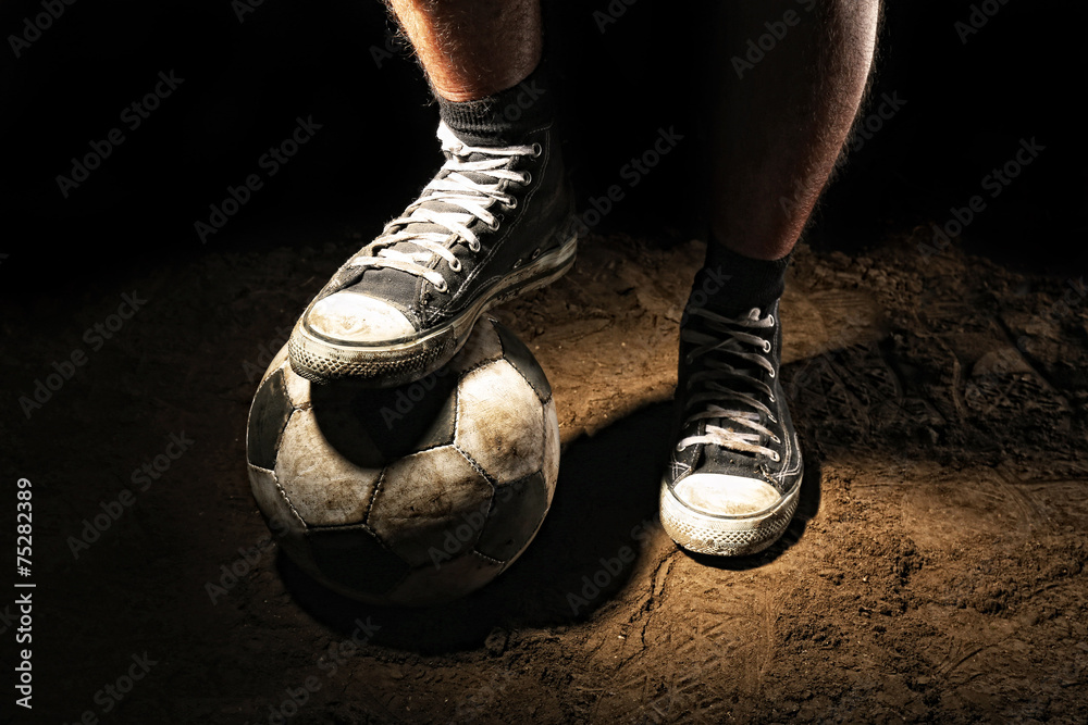 Poster Soccer ball on ground on dark background