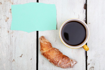 Composition of coffee, fresh croissant and paper card