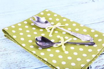 Metal spoons on green polka dot napkin on wooden background