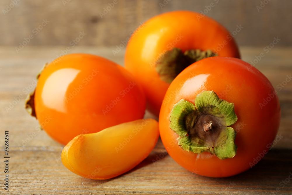 Poster ripe persimmon on color wooden background