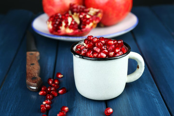 Juicy ripe pomegranate on wooden table, on dark background