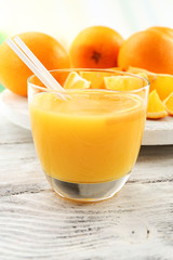 Glass of orange juice with straw and slices