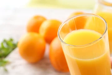 Fototapeten Glass of orange juice and oranges on wooden table background © Africa Studio