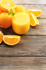 Glass of orange juice and slices on wooden table background