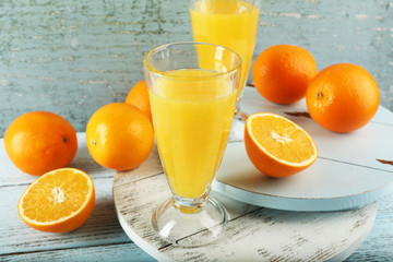 Glass of orange juice with slices on color wooden background