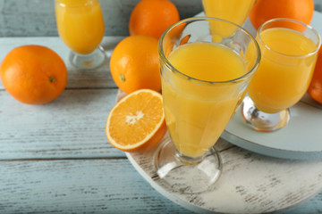 Glass of orange juice with slices on color wooden background