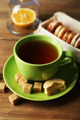 Colorful macaroons with cup of tea on wooden background