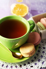 Colorful macaroons with cup of tea on wooden background