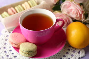 Colorful macaroons with cup of tea on wooden background