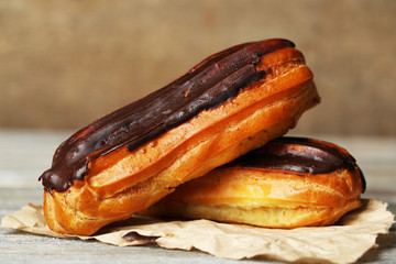 Tasty eclairs on wooden table, close up