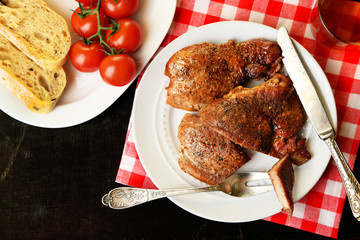 Roasted meat and vegetables on plate, on wooden table