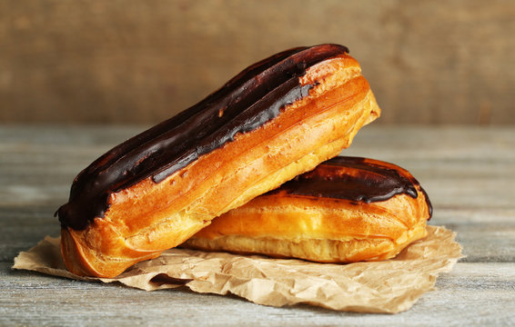 Tasty eclairs on wooden table, close up