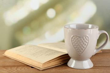 Cup of tea and book on table, on bright background
