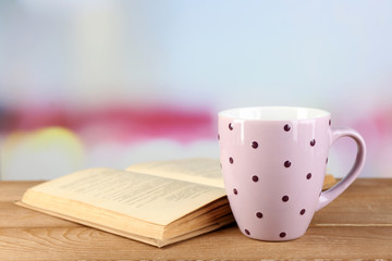 Cup of tea and book on table, on bright background