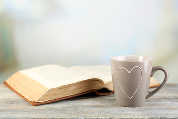Cup of tea and book on table, on light background