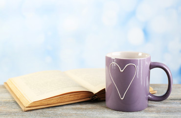 Cup of tea and book on table, on bright background
