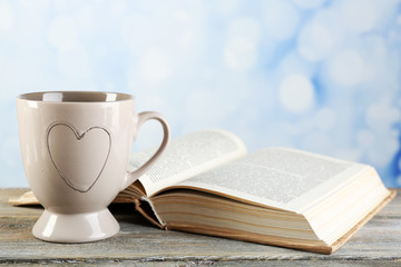 Cup of tea and book on table, on bright background