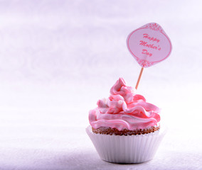 Delicious cupcake with inscription on table on beige background