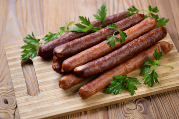 Wooden cutting board with smoked sausages, studio shot
