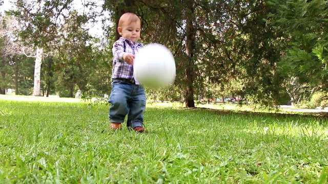 Cute little boy playing with soccer ball supported by his mother