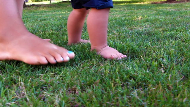 Cute baby boy making his first steps on grass