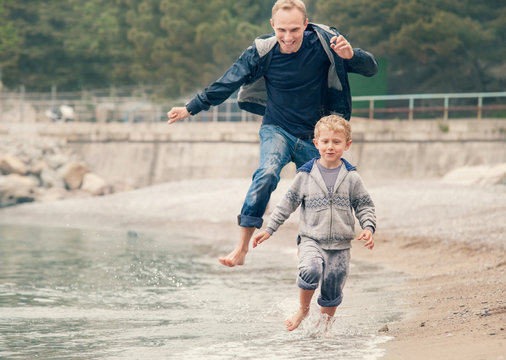 Father with son running on the sea surf line