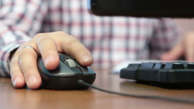 A hand controls computer mouse closeup