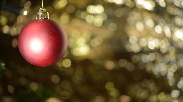 rotes Christbaumkugel vor hellem goldenen Hintergrund