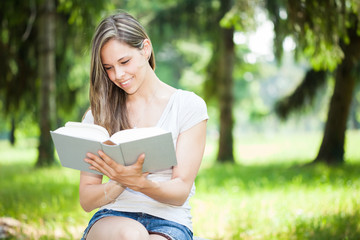 Fototapeta premium Young smiling woman reading a book