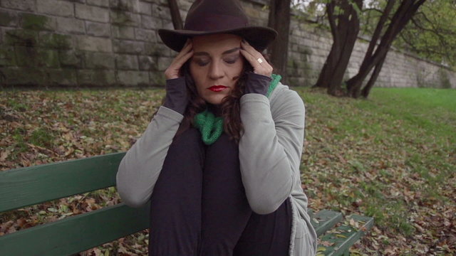 Woman sitting on the bench with headache, slow motion shot
