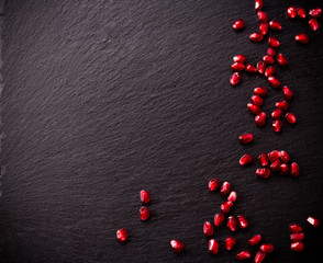 Pomegranate seeds on black slate background