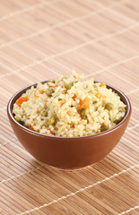 rice with vegetables in a ceramic bowl on a mat