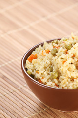 rice with vegetables in a ceramic bowl on a mat