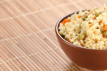 rice with vegetables in a ceramic bowl on a mat bamboo