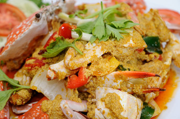 Fried crab in yellow curry on white plate,