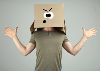Man with cardboard box on his head on grey background