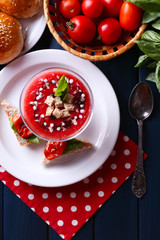 Gazpacho soup in glass bowl, on color wooden background