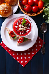 Gazpacho soup in glass bowl, on color wooden background