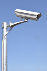 White security camera monitor on iron pole.